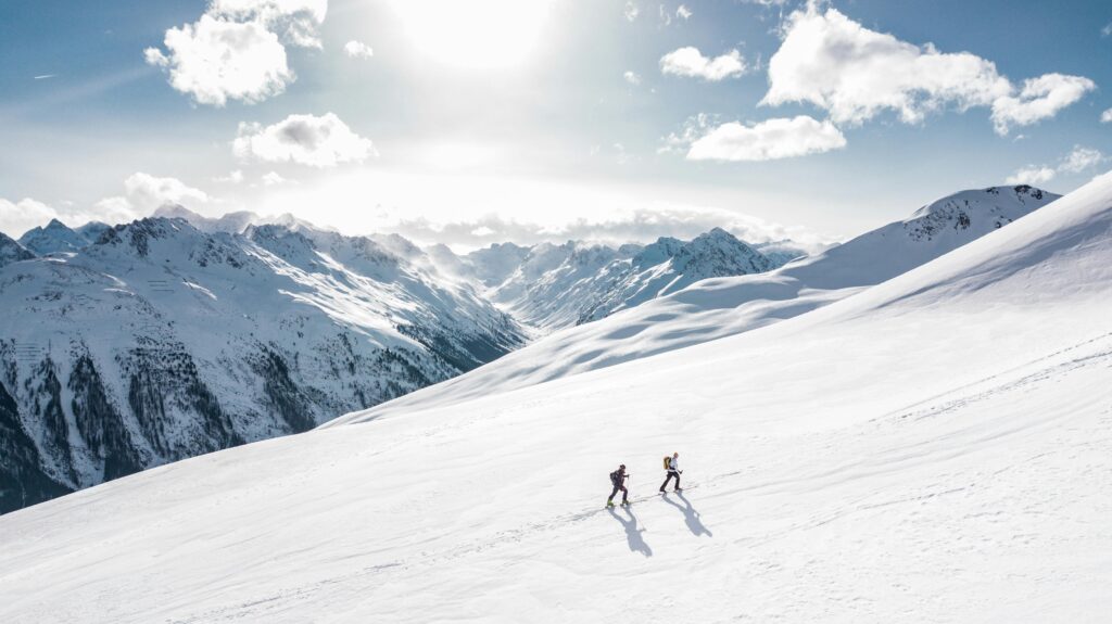two people walking up a mountain though the snow Image