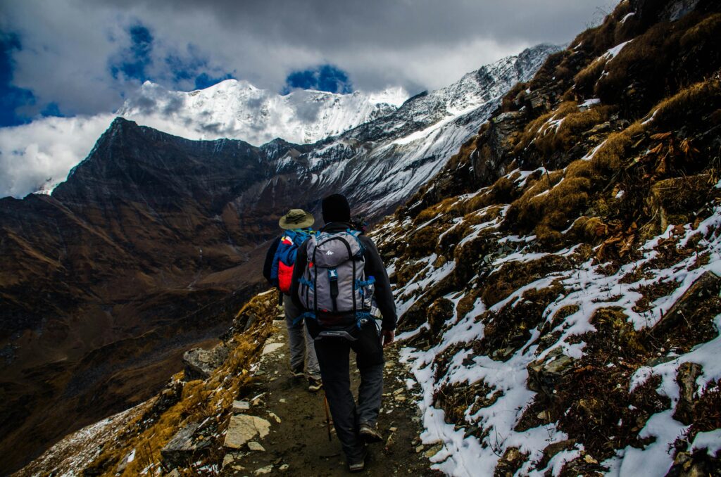 two people waling through snow capped mountains Image